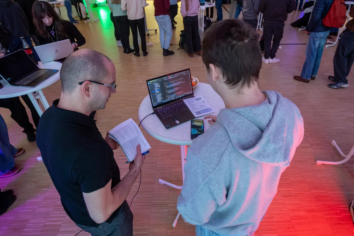 Two students look at program code on a laptop at a project exhibition