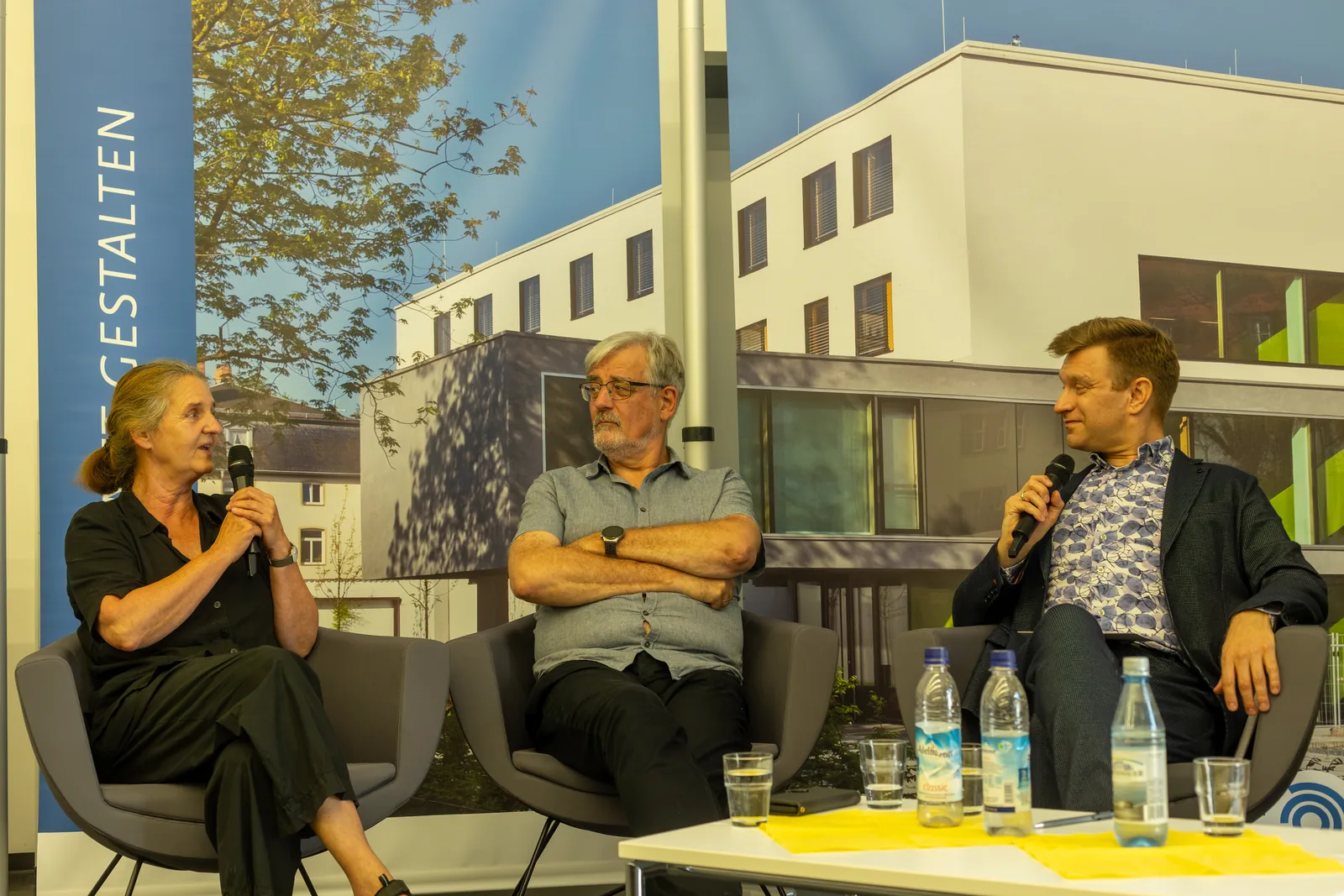Three people sit in armchairs on a stage and talk during a panel discussion
